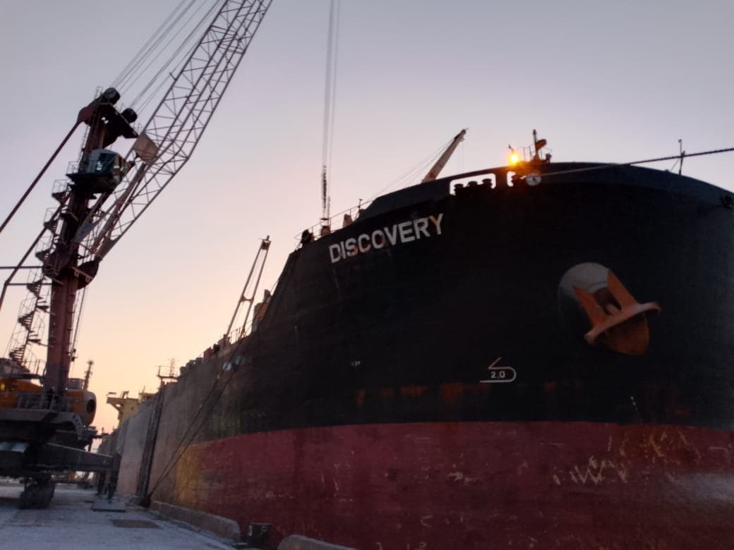 Bulk carrier at berth with quayside and deck cranes at first light