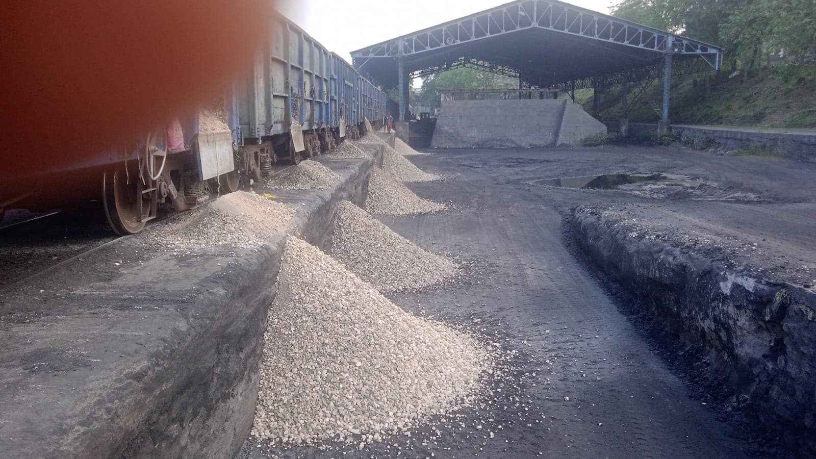 Row of aggregate heaps discharged from wagons alongside a covered storage shed