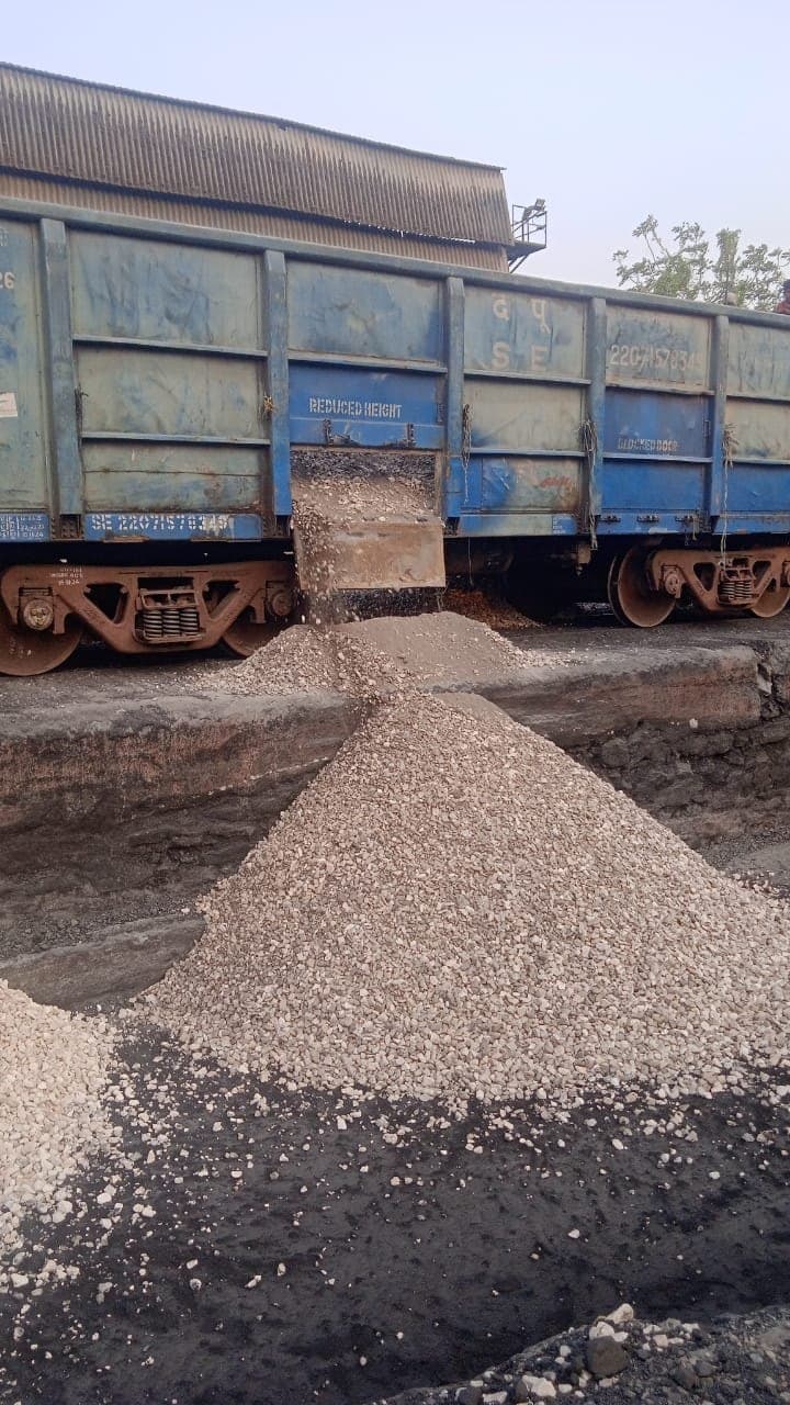 Aggregate discharging through a wagon chute onto a stockpile at a rail unloading point