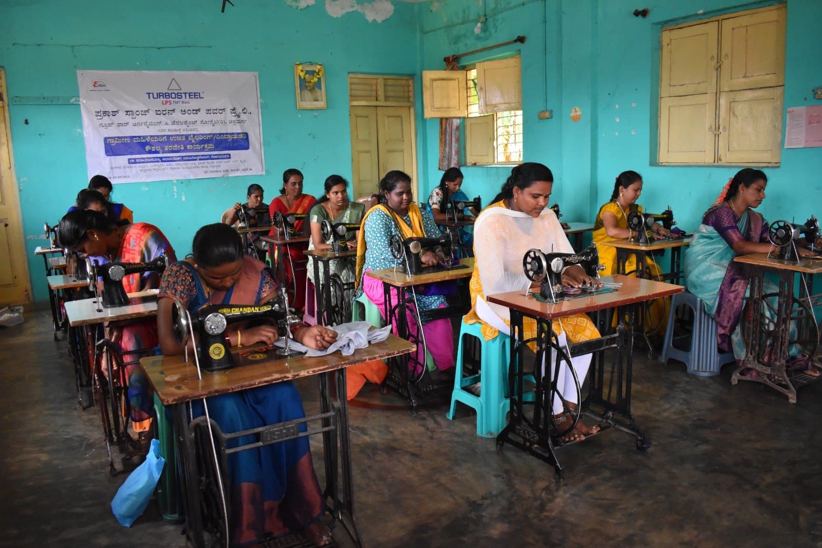Women at treadle sewing machines in a free tailoring skill training class