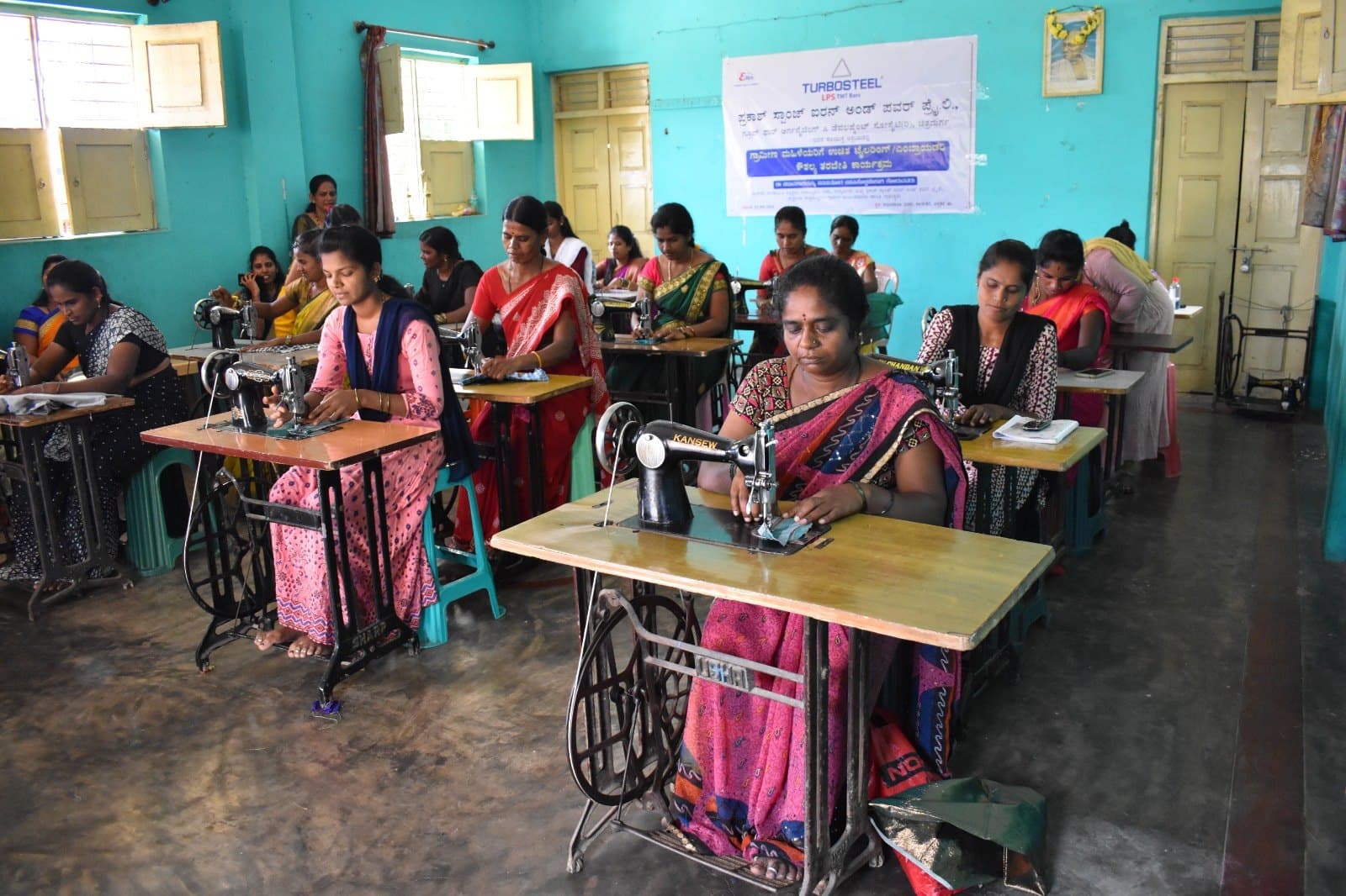 Classroom of rural women practising stitching on pedal sewing machines