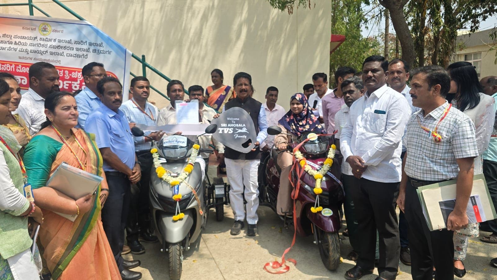 Officials hand over a symbolic key for garlanded scooters at a vehicle distribution event