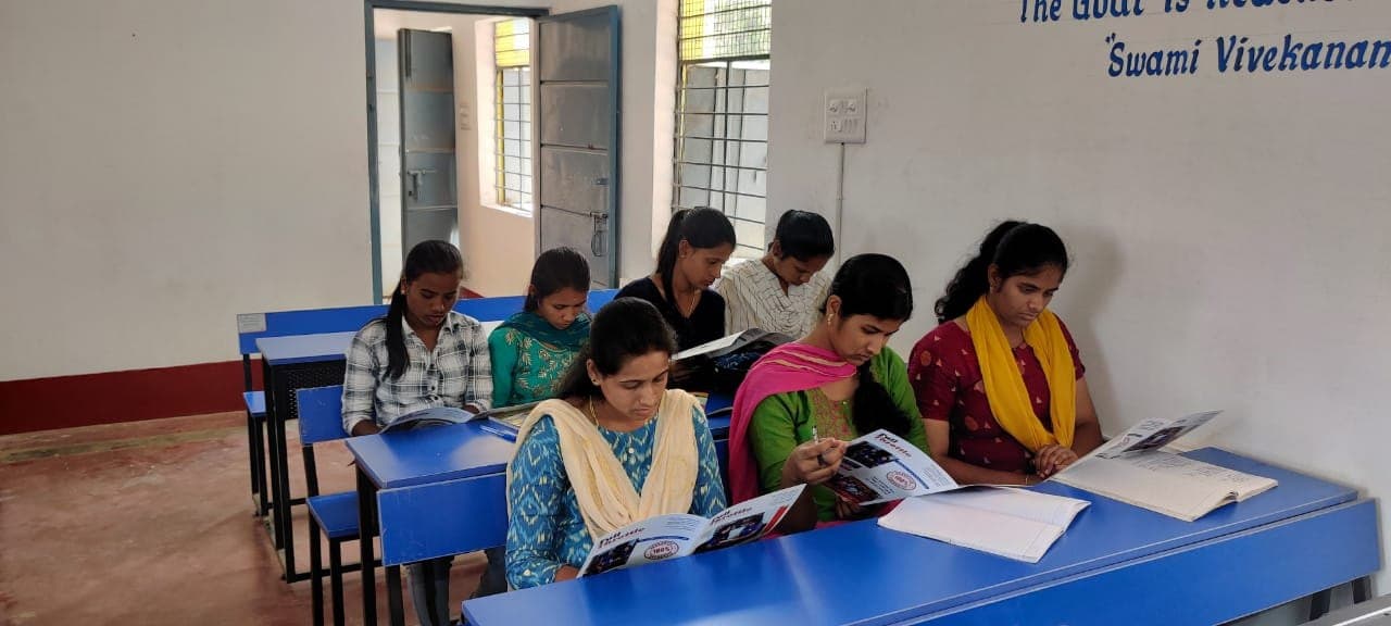 Young women reading course booklets at desks in a classroom session