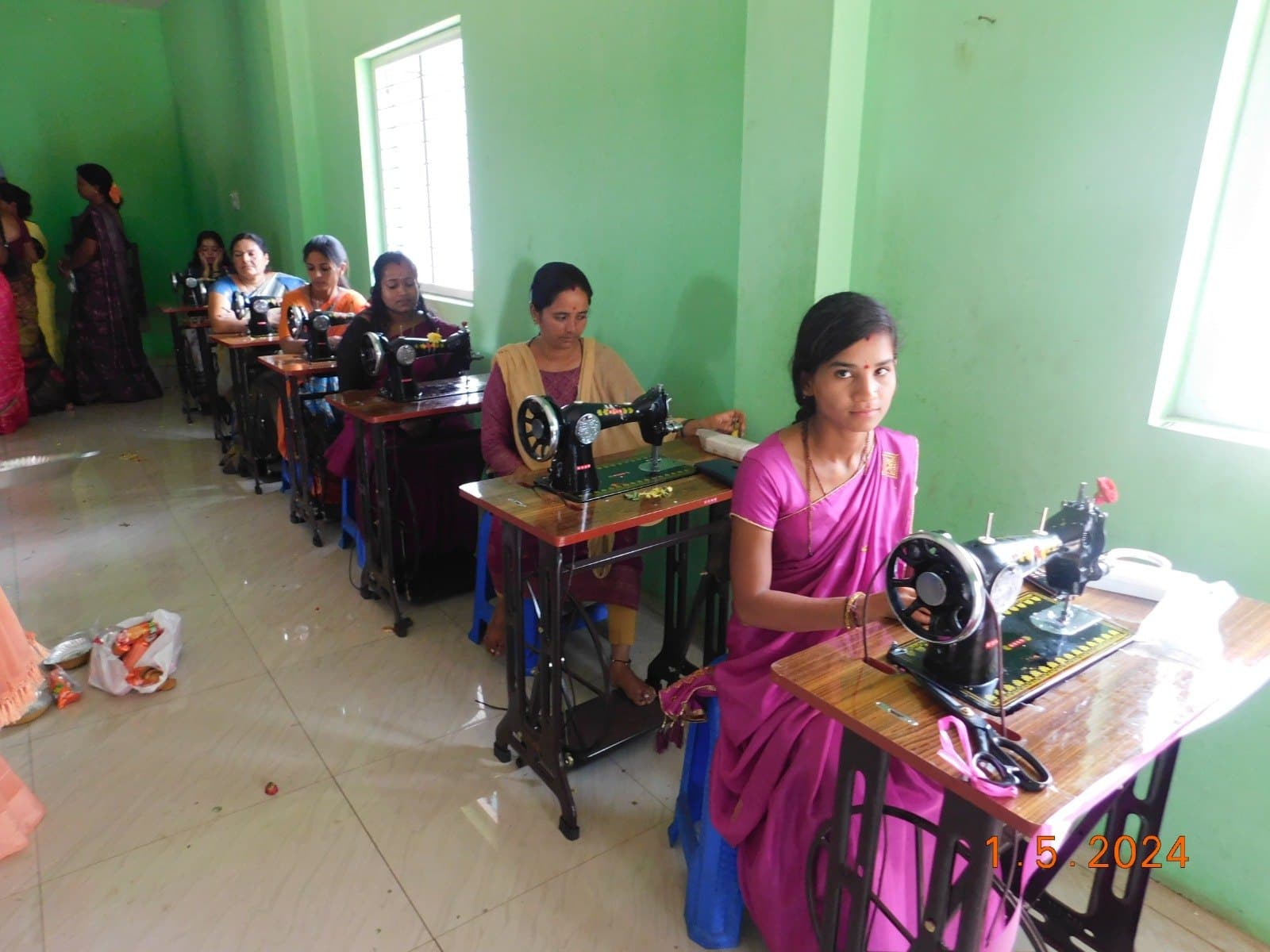 Row of women seated at new sewing machines in a freshly painted training hall